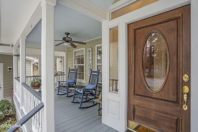 entrance to property featuring a porch, a ceiling fan, and visible vents