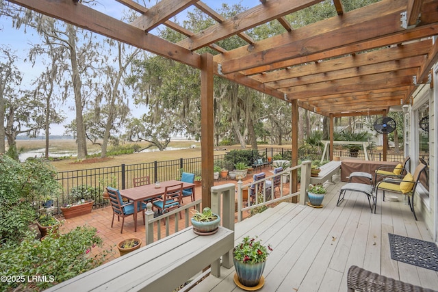deck featuring a pergola, outdoor dining space, a water view, and fence