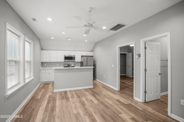 kitchen with visible vents, white cabinets, stainless steel appliances, and light wood-style floors