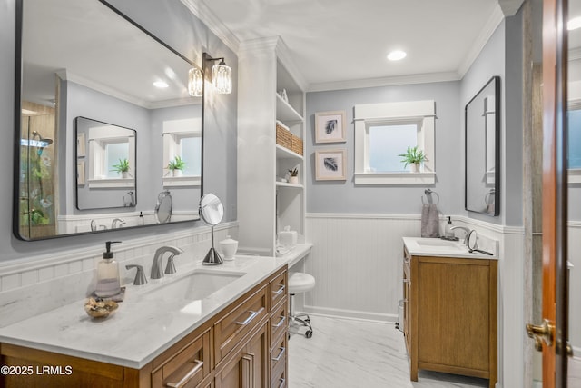 full bathroom featuring a wainscoted wall, crown molding, two vanities, and a sink