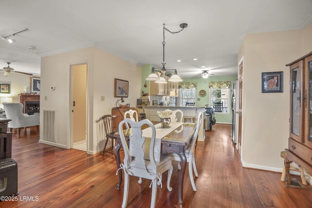 dining space with baseboards, wood finished floors, a ceiling fan, and crown molding