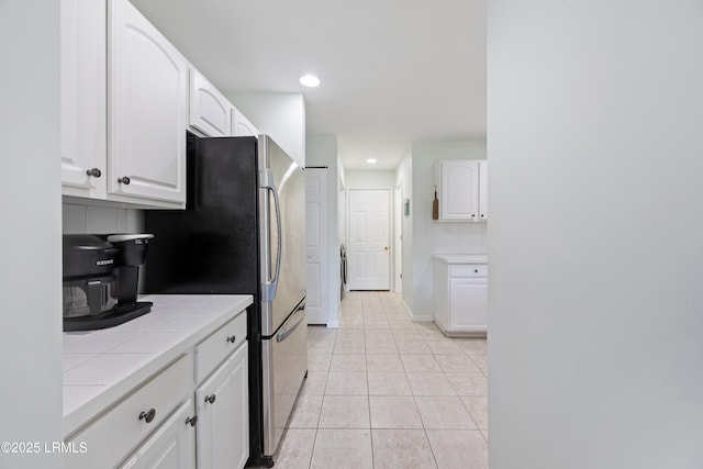 52 Lake Linden Ln Unit 52, Bluffton, SC 29910 - kitchen featuring tile countertops, decorative backsplash, white cabinets, freestanding refrigerator, and light tile patterned floors