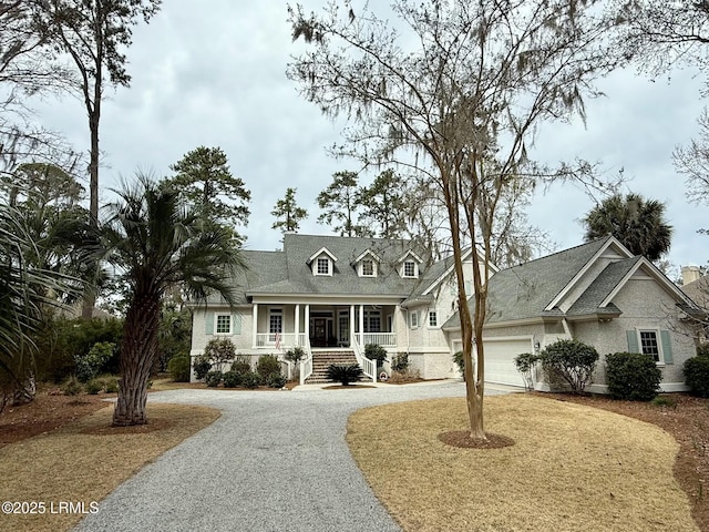 cape cod-style house featuring a porch, a garage, and gravel driveway