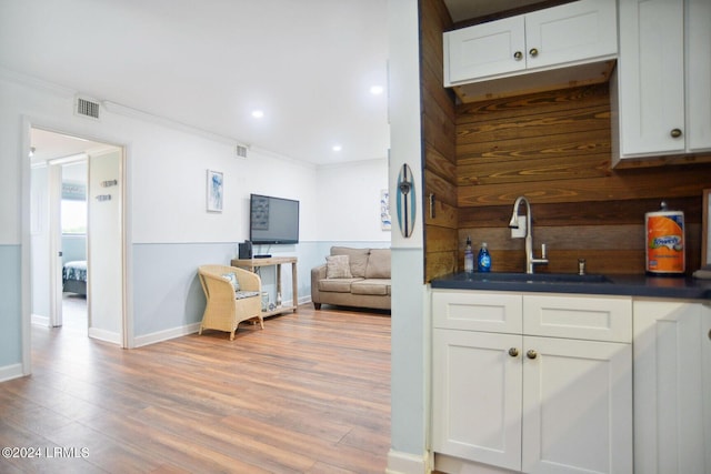 kitchen featuring white cabinetry, crown molding, light hardwood / wood-style floors, and sink