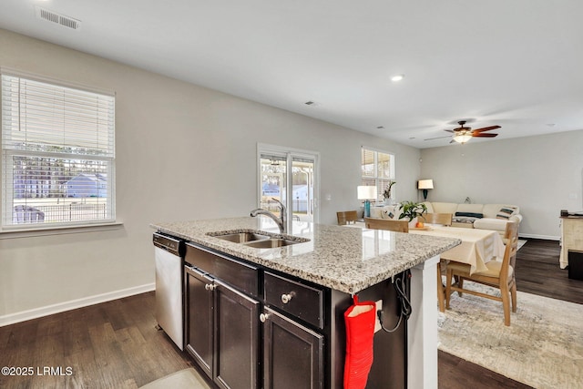 kitchen featuring sink, light stone counters, a center island with sink, dark hardwood / wood-style flooring, and stainless steel dishwasher