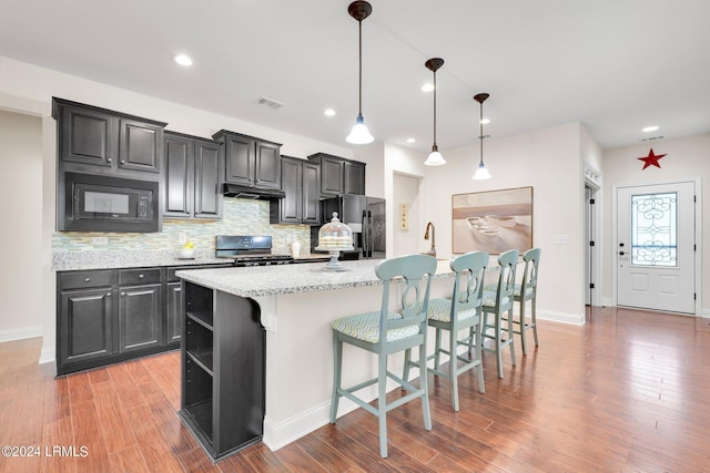 kitchen featuring range, a kitchen island with sink, tasteful backsplash, a kitchen bar, and stainless steel fridge with ice dispenser