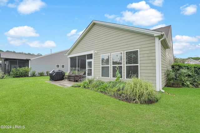 rear view of property featuring a sunroom, a patio, and a lawn