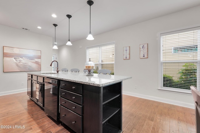 kitchen with sink, hanging light fixtures, light stone counters, stainless steel dishwasher, and light wood-type flooring