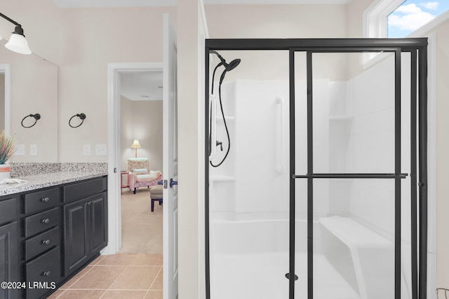 bathroom with a shower with door, vanity, and tile patterned flooring