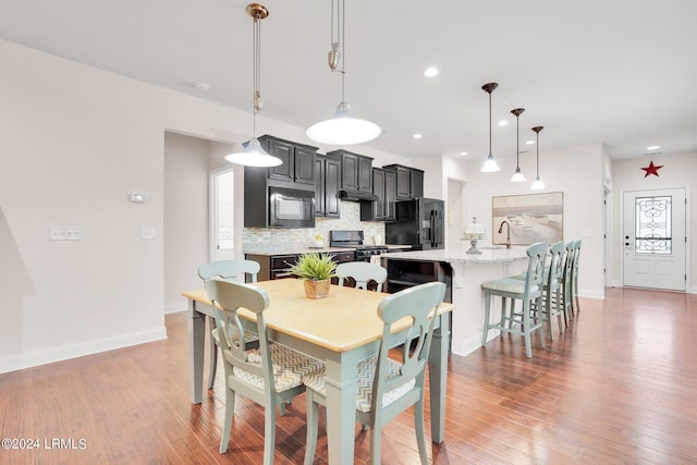 dining area featuring sink, light hardwood / wood-style floors, and beverage cooler