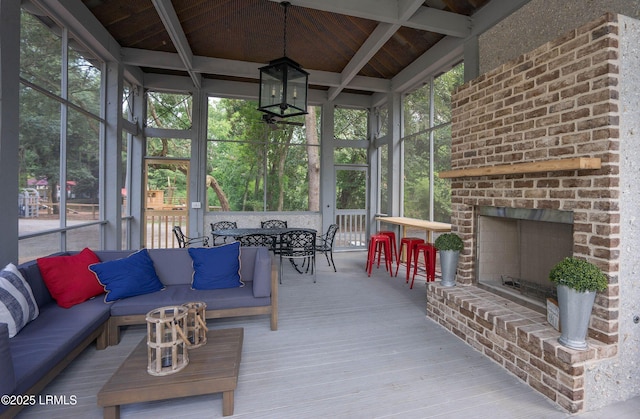 sunroom / solarium with an outdoor brick fireplace, lofted ceiling with beams, and a wealth of natural light