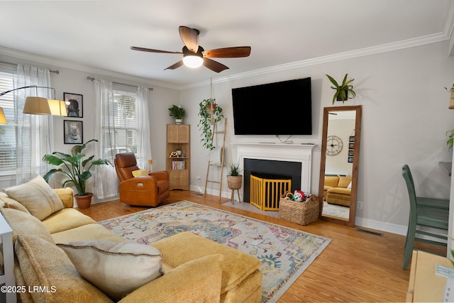 living room featuring ceiling fan, ornamental molding, and light wood-type flooring