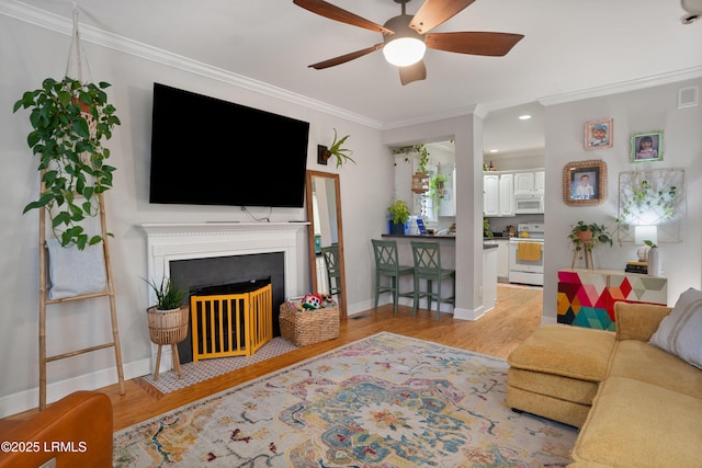 living room featuring crown molding, ceiling fan, and light hardwood / wood-style floors