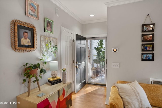 foyer with ornamental molding and light hardwood / wood-style floors