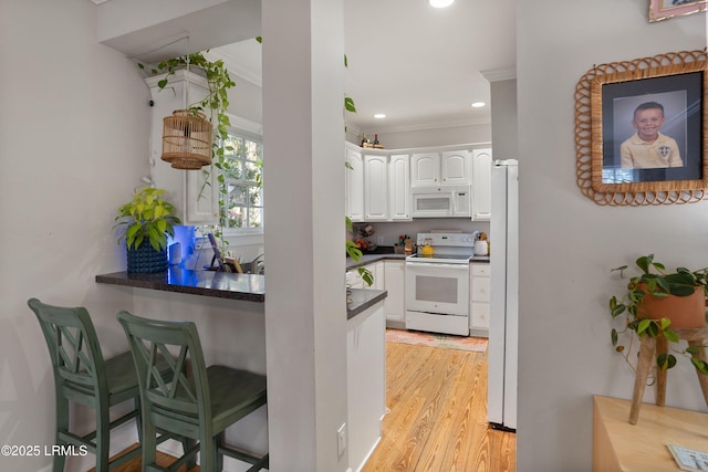 kitchen with white appliances, light hardwood / wood-style flooring, ornamental molding, and white cabinets