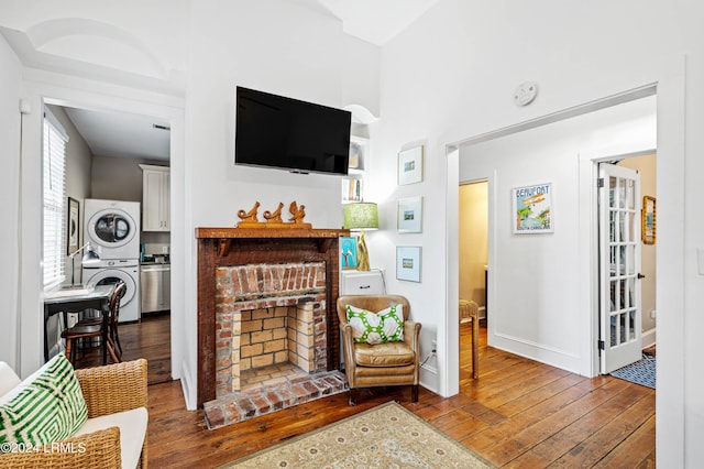 living room featuring dark wood-type flooring, stacked washer / dryer, and a fireplace