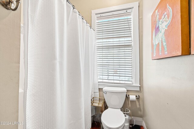 bathroom with a shower with curtain, a wealth of natural light, and toilet