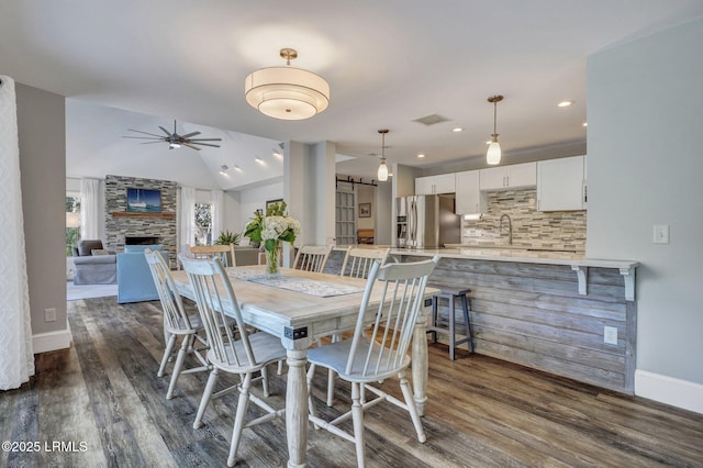 dining area featuring vaulted ceiling, a barn door, sink, and dark hardwood / wood-style flooring