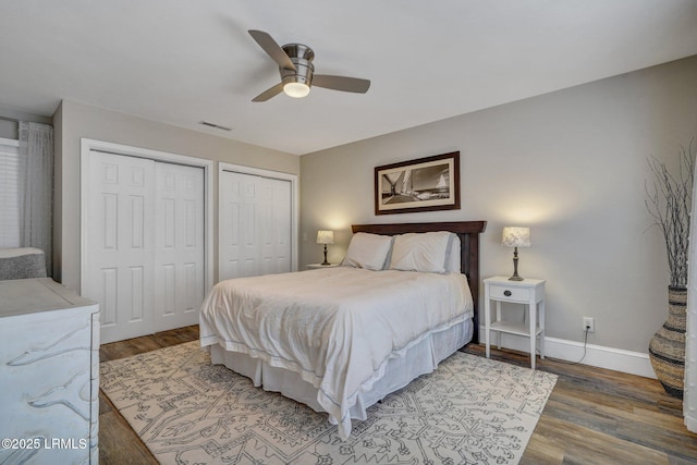 bedroom featuring hardwood / wood-style floors, two closets, and ceiling fan