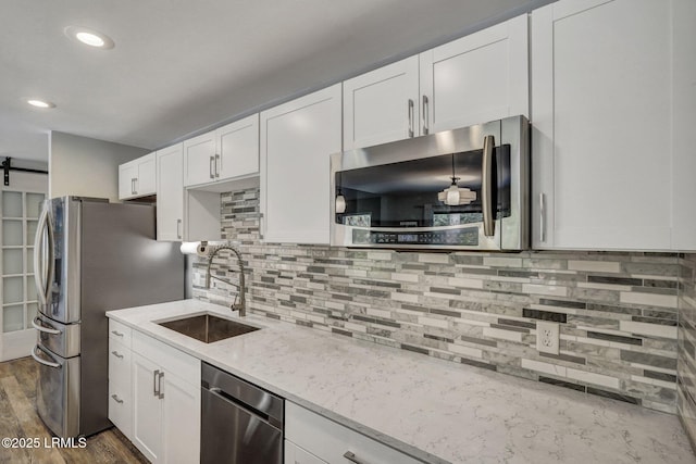 kitchen featuring sink, appliances with stainless steel finishes, light stone counters, white cabinets, and decorative backsplash