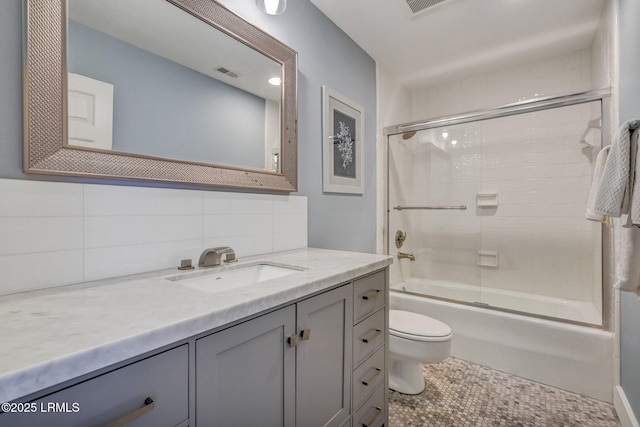 full bathroom with enclosed tub / shower combo, vanity, decorative backsplash, and toilet