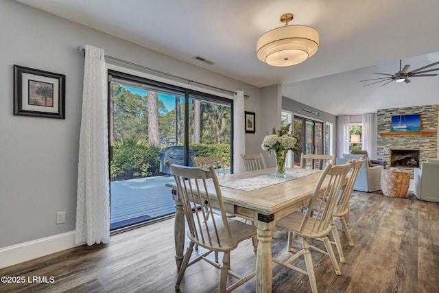 dining room featuring lofted ceiling, hardwood / wood-style floors, a fireplace, and ceiling fan