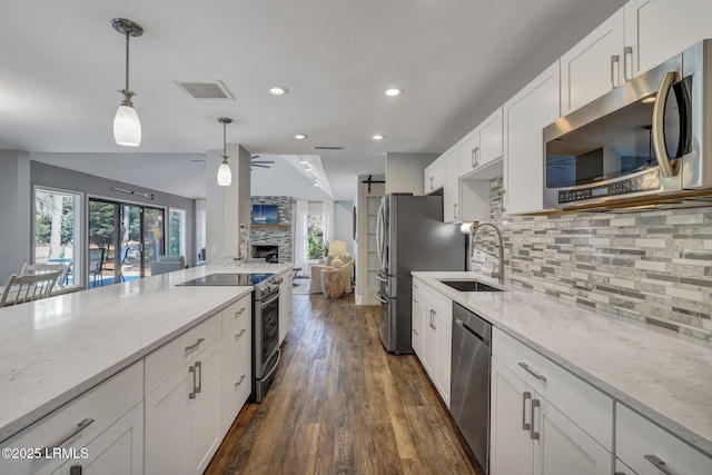 kitchen featuring decorative light fixtures, sink, white cabinets, light stone counters, and stainless steel appliances