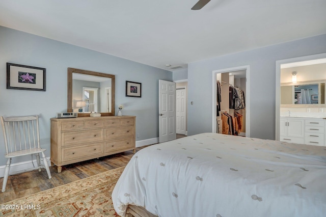 bedroom with light hardwood / wood-style flooring, a spacious closet, ceiling fan, ensuite bath, and a closet