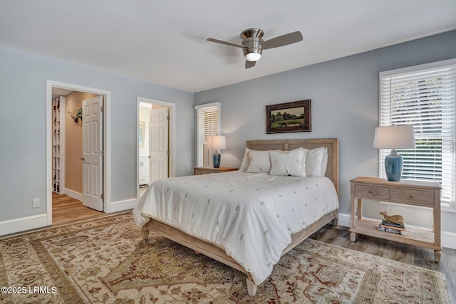 bedroom featuring connected bathroom, a walk in closet, wood-type flooring, and ceiling fan