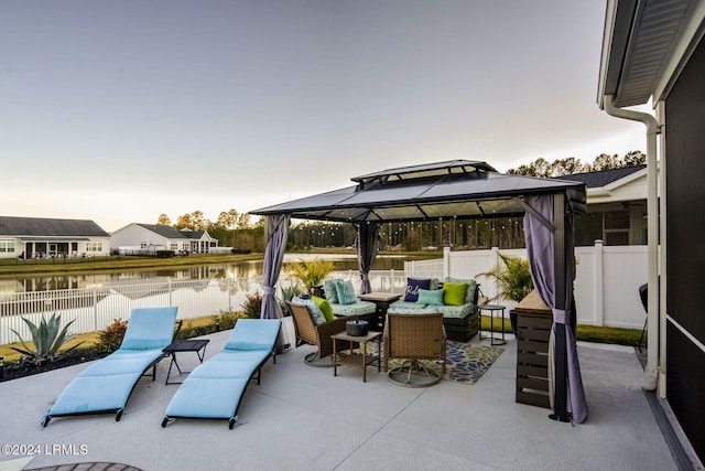 patio terrace at dusk with a gazebo, a water view, and an outdoor living space