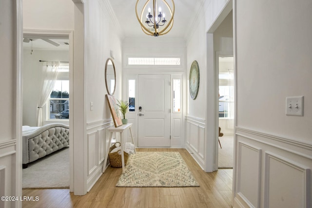 entryway featuring crown molding, a chandelier, and light wood-type flooring