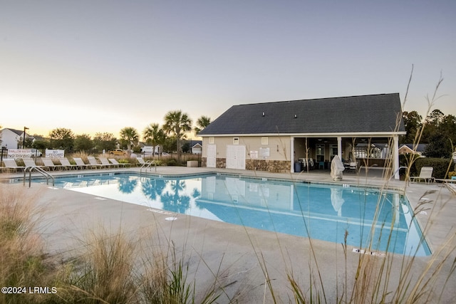 pool at dusk with a patio area