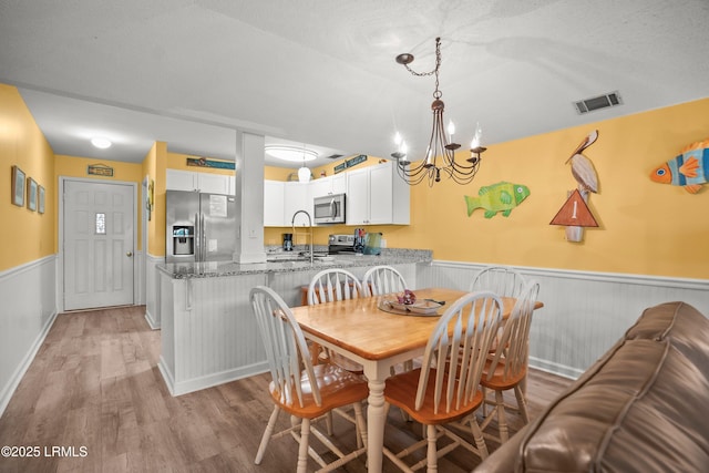167 Beach Club Villa Dr Unit 167, Fripp Island, SC 29920 - dining area with a wainscoted wall, light wood finished floors, and a chandelier