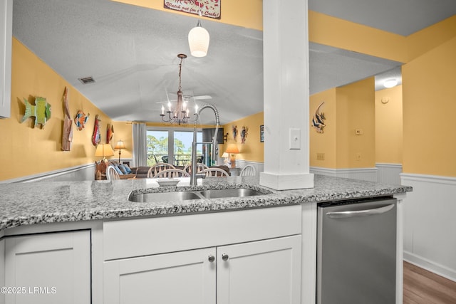 167 Beach Club Villa Dr Unit 167, Fripp Island, SC 29920 - kitchen with stainless steel dishwasher, wainscoting, a chandelier, wood finished floors, and white cabinetry