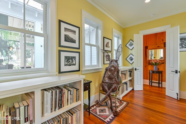 living area with baseboards, wood finished floors, and ornamental molding