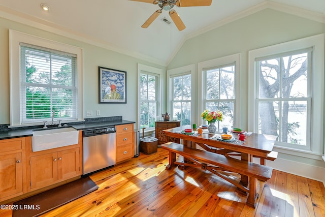 kitchen with a sink, vaulted ceiling, crown molding, stainless steel dishwasher, and dark countertops