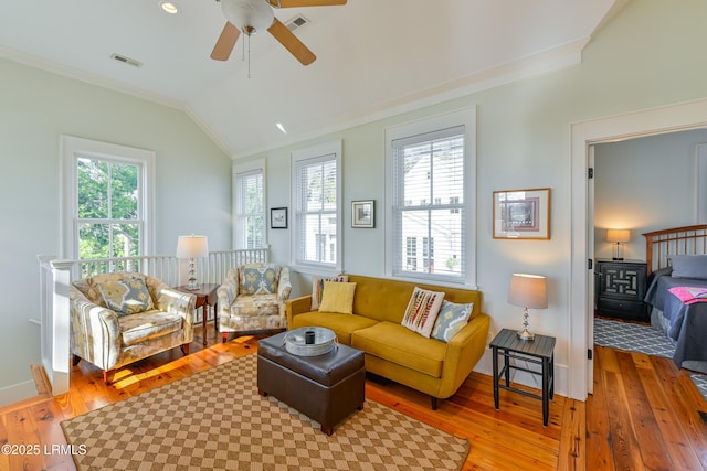 living area with a wealth of natural light, visible vents, hardwood / wood-style floors, and vaulted ceiling