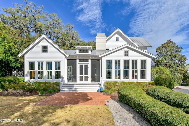 back of property featuring a standing seam roof, a sunroom, and metal roof