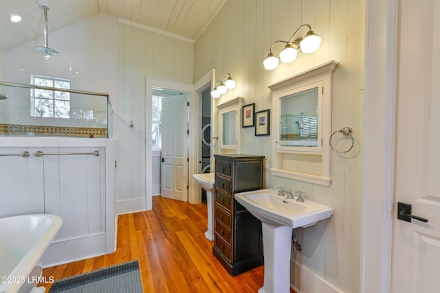 bathroom with walk in shower, wood finished floors, vaulted ceiling, a freestanding tub, and a sink