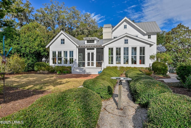 rear view of house with a lawn, a sunroom, and metal roof