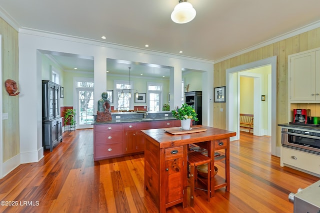 kitchen featuring dark countertops, light wood-style flooring, ornamental molding, and a sink