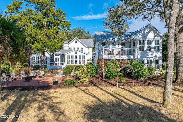 rear view of house featuring a patio area, a sunroom, and an outdoor fire pit