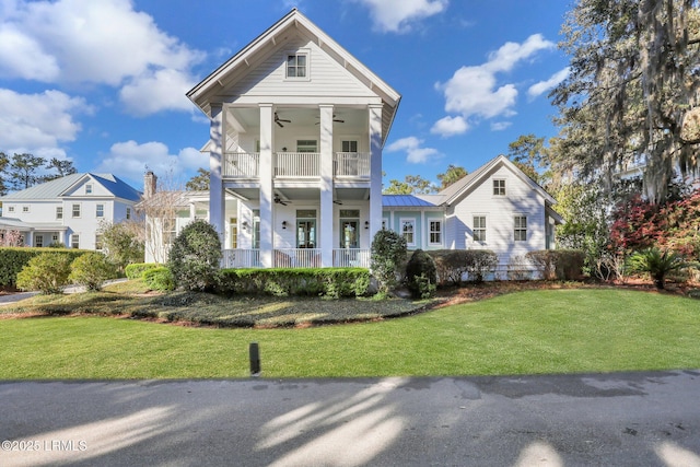 neoclassical home with a standing seam roof, ceiling fan, a front lawn, and a balcony