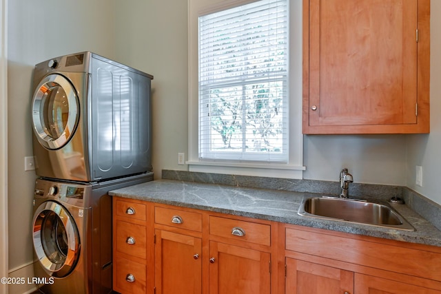 laundry area with stacked washer and dryer, cabinet space, and a sink