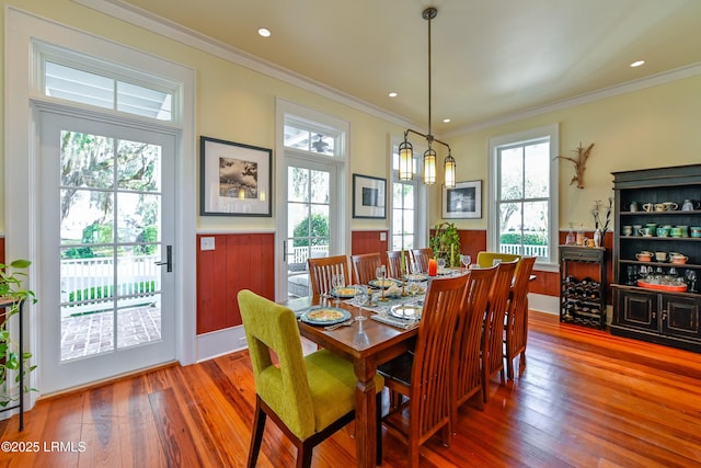 dining space with recessed lighting, a wainscoted wall, wood-type flooring, and ornamental molding