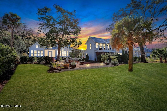 rear view of property with a lawn, a fire pit, and a patio