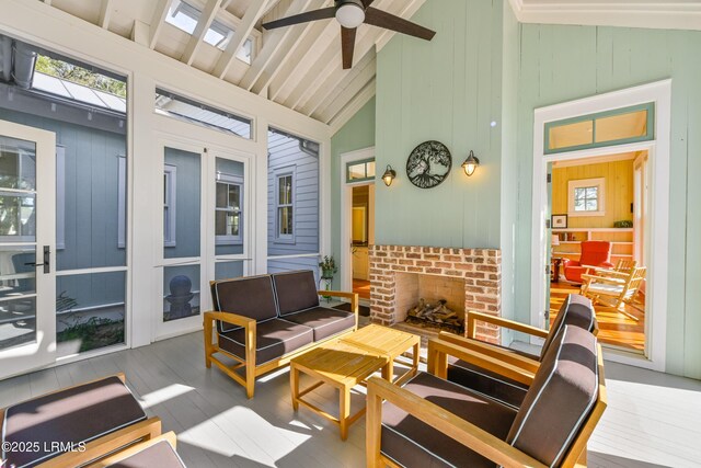 sunroom featuring a ceiling fan, a brick fireplace, vaulted ceiling with beams, and a healthy amount of sunlight