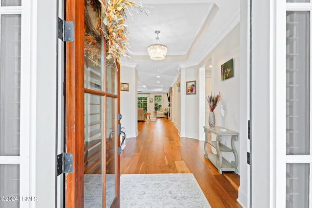 hallway with crown molding, a chandelier, light wood-type flooring, and french doors