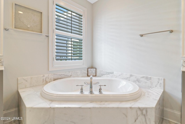 bathroom with tiled tub and plenty of natural light