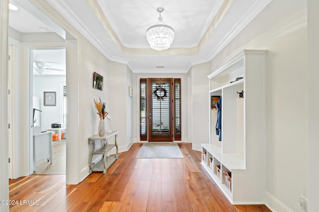 mudroom with a raised ceiling, ornamental molding, an inviting chandelier, and light wood-type flooring